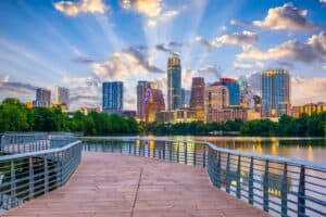 A vibrant cityscape of Austin, Texas, featuring modern skyscrapers, a scenic waterfront, and a colorful sunset sky, ideal for urban development and architecture themes.